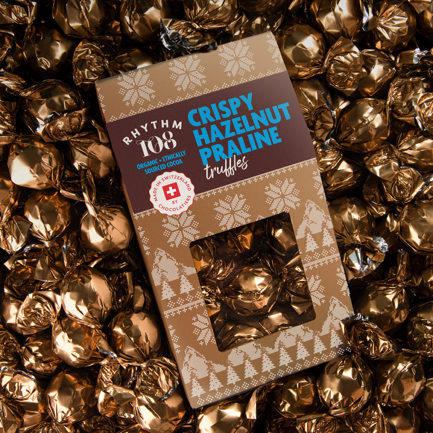 Box of Rhythm of  Crispy Hazelnut Praline truffles surrounded by gold wrappers.